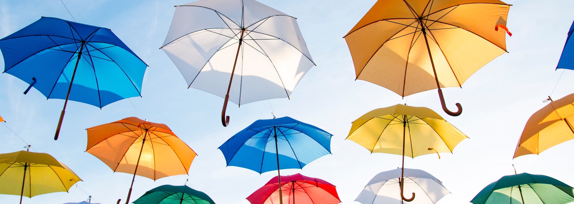 multi-colored umbrellas floating in a blue sky